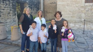 Dorothy Schultze, co-chair of Junior Associates Committee, Pam Rosser, Alamo Conservator, and Virginia Van Cleave, chair of Junior Associates committee stand with four Junior Associates and Emily Margaret during their visit to the Alamo!